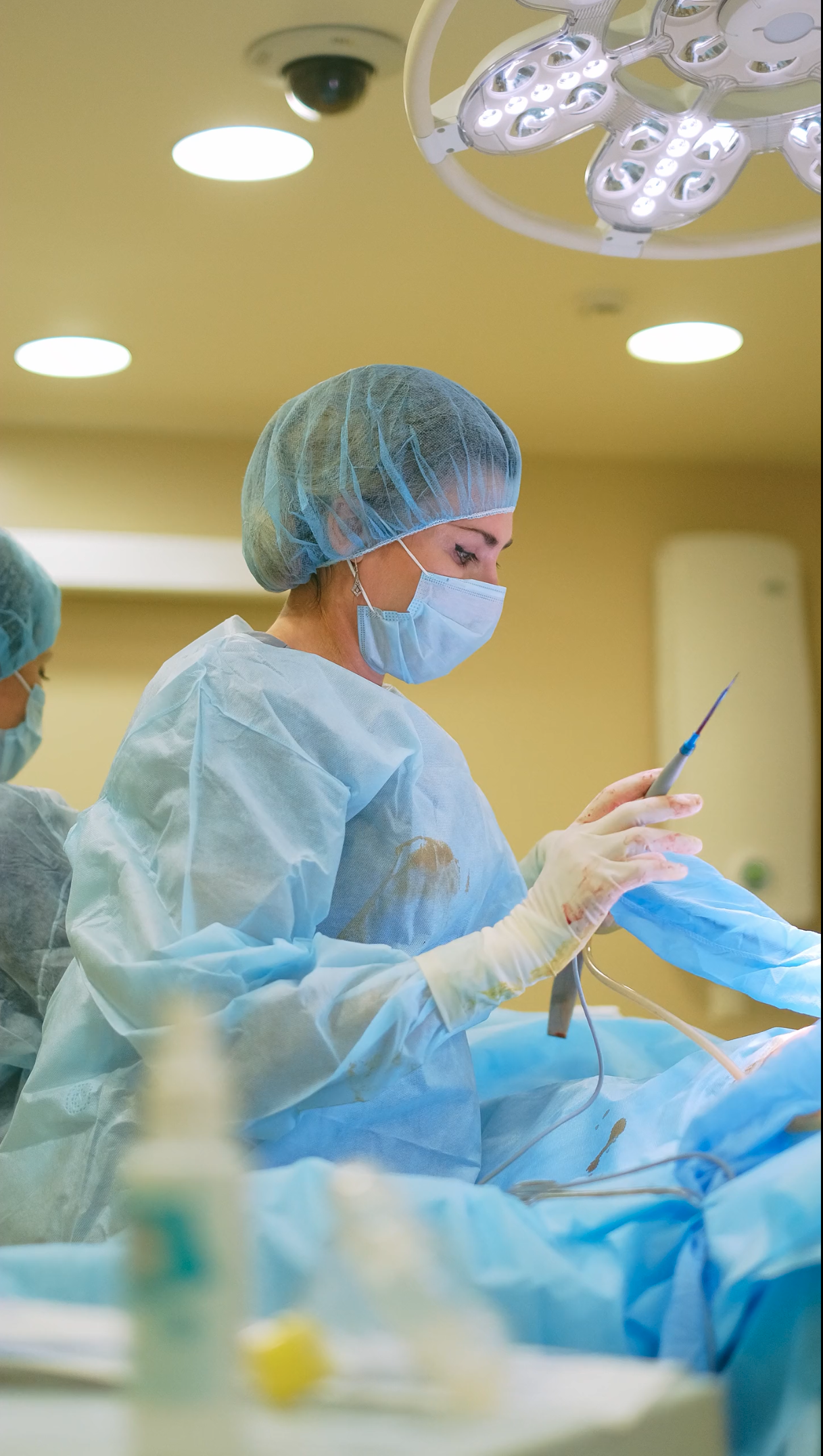 female surgeon holds medical instrument while operating